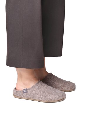 Pantofole in lana marrone con una texture morbida, punte arrotondate e suola piatta. Presentano un piccolo etichetta sul lato vicino all'apertura.