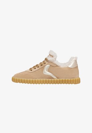Beige suède sneakers met een gestructureerde gouden rubberen zool, metallic gouden accenten en een pluche, vachtachtige kraag rond de opening.