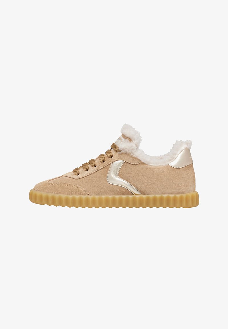Beige Wildleder-Sneaker mit einer strukturierten goldenen Gummisohle, metallisch goldenen Akzenten und einem plüschigen, fellartigen Kragen um die Öffnung.