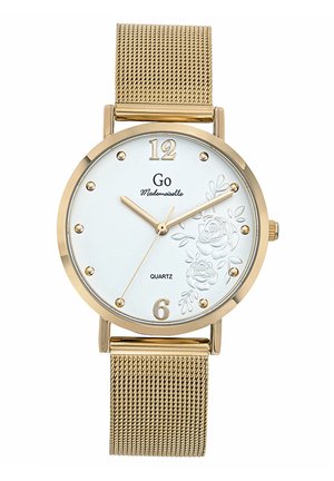 Montre en quartz dorée avec un cadran blanc à motif floral en relief, index en or, et un bracelet en maille. Présente des indications numériques à 12 et 6 heures.