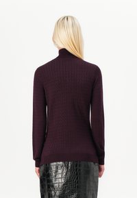 Dark purple turtleneck sweater with ribbed texture and long sleeves, featuring a fitted silhouette. Worn with a black textured skirt.