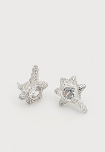 Ασημένια σκουλαρίκια σε σχήμα αστεριού με υφασμένες επιφάνειες και κεντρικούς διαφανείς πολύτιμους λίθους. Λαμπερές λεπτομέρειες ενισχύουν το σχέδιο.