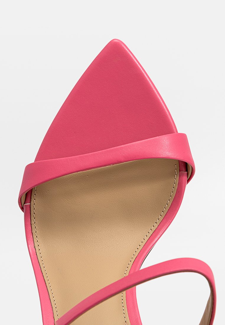 Sandale à talons hauts en cuir rose avec un bout pointu, une fine bride de cheville et une doublure intérieure lisse. La semelle est de couleur neutre avec des coutures visibles.