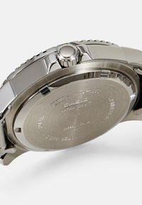 Silver stainless steel watch with a polished finish, featuring a round case, a crown, and engraved back. The design is sleek and modern.