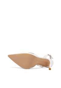 Zapato de tacón alto blanco con punta afilada, tira transparente y suela texturizada. Presenta un tacón delgado y un diseño minimalista.