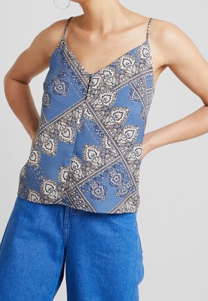 Blå mønstrede tanktop med tynde stropper, med paisley designs og en knapdetalje foran. Sammen med højtaljede blå jeans.