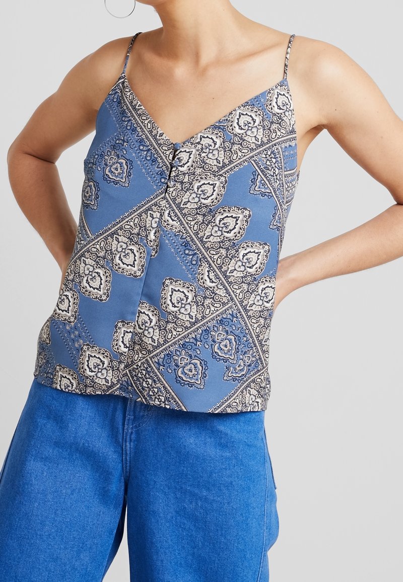 Top a spalla blu con motivo a paisley e spalline sottili, dotato di un dettaglio con bottoni sul davanti. Abbinato a jeans blu a vita alta.
