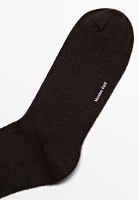 Calzino nero, textured, con punta arrotondata e un dettagliato logo discreto sul lato. Realizzato in materiale morbido, offre una vestibilità confortevole.