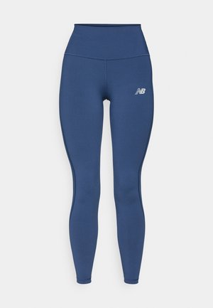 Tumedad sinised retuusid venivast kangast, millel on kõrge vöökoht ja diskreetne logo vasakul küljel, ning sile, mati viimistlusega.