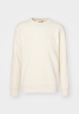 Sweatshirt couleur crème en tissu doux, avec un col rond et un logo "Timberland" en relief sur le devant. Manches longues avec bord-côtes.