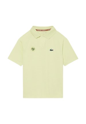 Hellgelbes Polo-Shirt mit Roland-Garros-Logo auf der linken Brustseite und grünem Lacoste-Krokodil-Logo auf der rechten Brustseite.