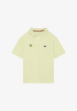 Hellgelbes Polo-Shirt mit Roland-Garros-Logo auf der linken Brustseite und grünem Lacoste-Krokodil-Logo auf der rechten Brustseite.