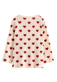 Ljust beige långärmad topp med ett upprepande mönster av röda hjärtan. Tyget har en texturerad, ribbad design.