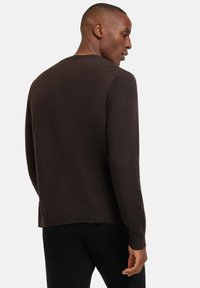 Brauner Strickpullover mit rundem Halsausschnitt, gerippter Textur am Saum und den Bündchen, taillierter Silhouette und weichem Material. Sieht nach mittlerem Gewicht aus.