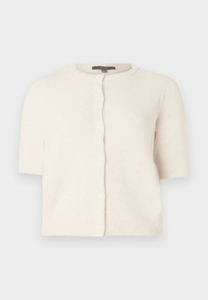 Kortermet cardigan i myk, kremfarget strikk. Har rund hals, knappestolpe foran og ribbestrikket kant og mansjetter for tekstur.