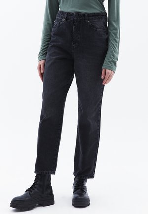 Zwarte high-waisted jeans van denim, met een rechte pijp en een vijf-pocketstijl. Gecombineerd met zwarte veterschoenen.