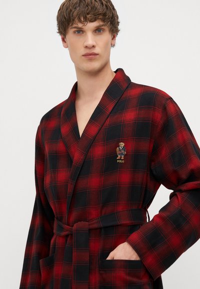 Raudonas ir juodas langeliais chalatas, pagamintas iš minkštos medžiagos. Turi šaliką, diržą ir logotipo pleistrą. Įtraukti šoniniai kišeniai ir laisvas kirpimas.