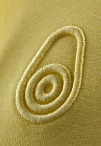 Broderet logo på struktureret gul stof, med et spiraldesign i matchende gule tråde, der viser en glat overflade og rene linjer.