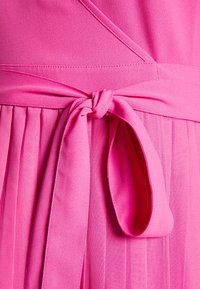Ein pinkes Kleid aus strukturiertem Stoff mit Falten, das an der Taille mit einem gebundenen Gürtel gerafft ist. Das Design umfasst glatte, fließende Formen.