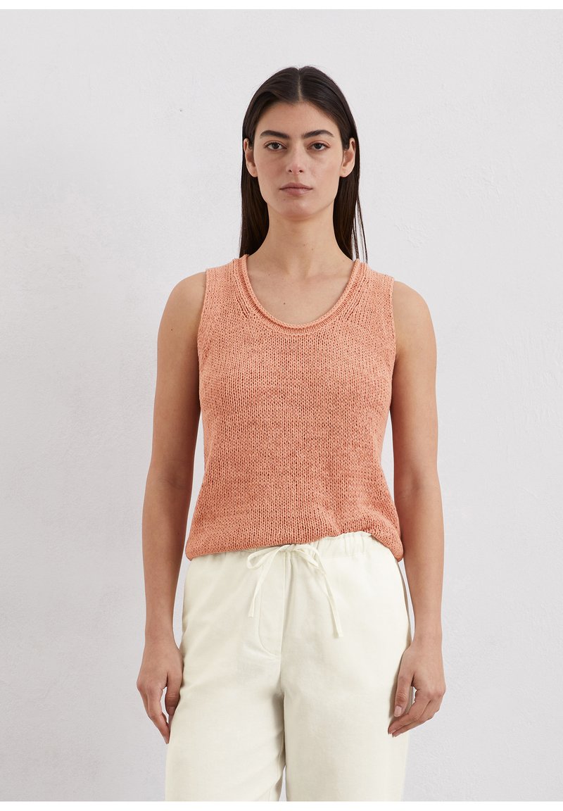 Perzik gebreid tanktop met een ronde halslijn en mouwloos ontwerp; heeft een losse pasvorm en een gestructureerde stof. Gecombineerd met lichtbeige broeken.