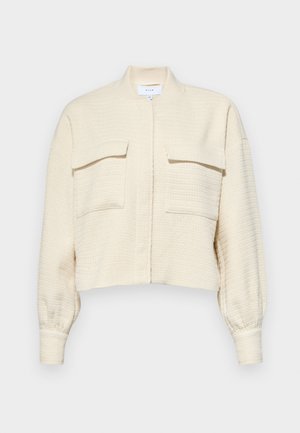 Kopts krēmkrāsas žakete ar teksturētu audumu, ar rāvējslēdzēja priekšu, uzceltu apkakli un divām krūšu kabatām ar pogu uzlādes flāpām.