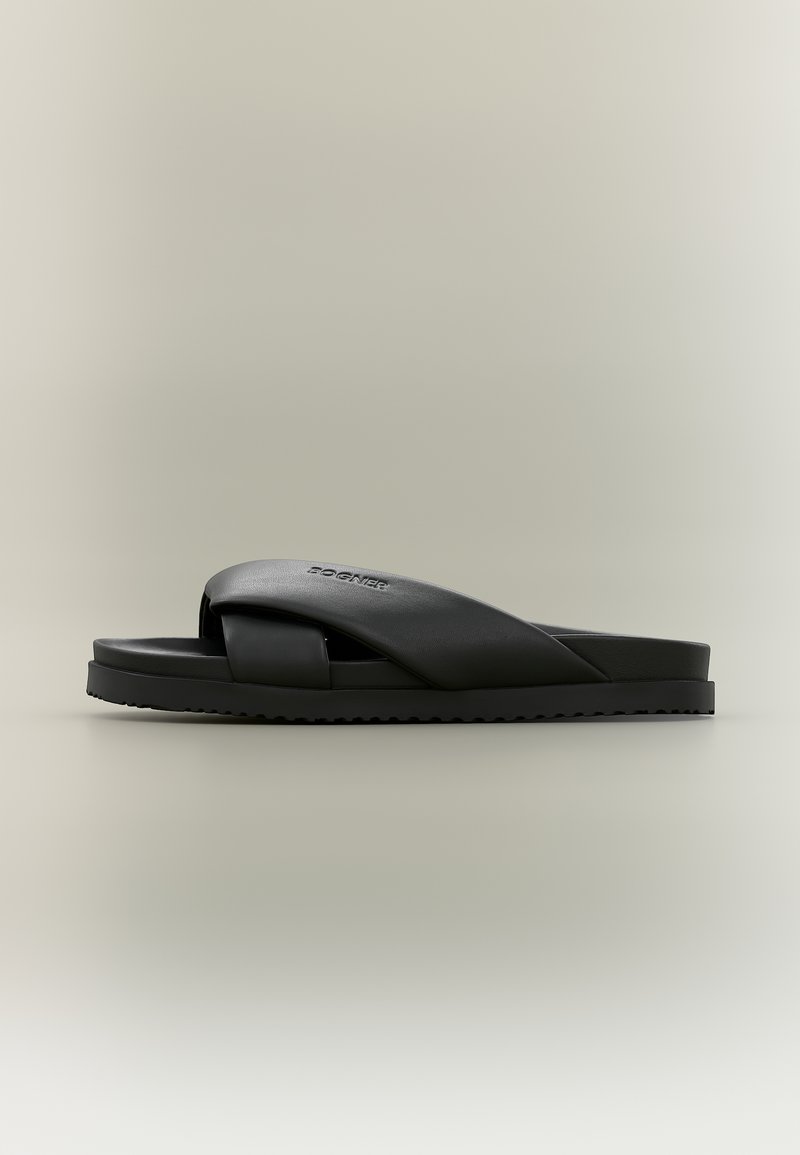 Sandale noire à talon avec larges brides croisées et semelle texturée sur fond neutre.