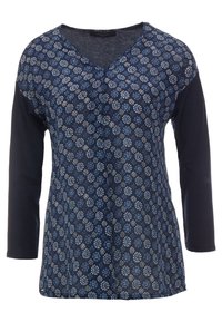 Tunika purjehtijan kukkakuviolla, jossa on kolme neljänneksen pituiset hihat, V-kaula-aukko sekä kevyttä kangassekoitetta, jossa on tummemmat yksiväriset hihat.