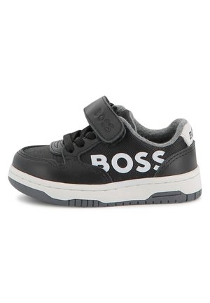 Baskets noires en matériau synthétique, avec un logo "BOSS" blanc, des accents en textile, des lacets et une sangle en Velcro. Semelle blanche avec des accents gris.