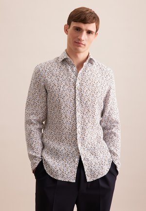 Langarmshirt aus leichtem Stoff mit einem mehrfarbigen Blumenmuster auf weißem Hintergrund, klassischem Kragen und geschwungenem Saum.