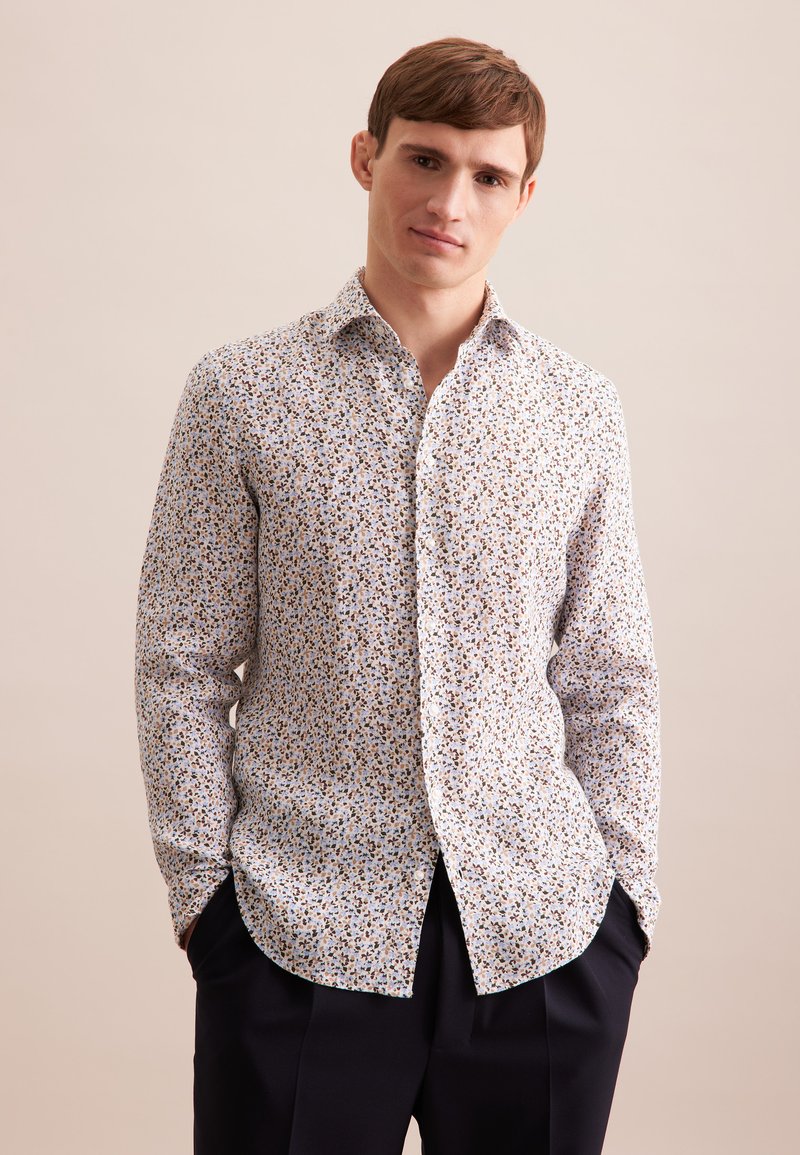 Langarmshirt van lichtgewicht stof, met een kleurrijk bloemenpatroon op een witte achtergrond, voorzien van een klassieke kraag en een afgeronde zoom.