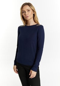 Marine blauwe gebreide trui met lange mouwen, ronde hals en decoratieve kraalaccenten op de schouders. Glad textuur en slimfit ontwerp.