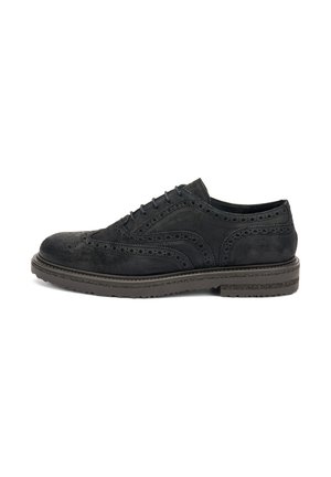 Scarpa brogue in suede nero con perforazioni dettagliate e una spessa suola in gomma, vista di lato.
