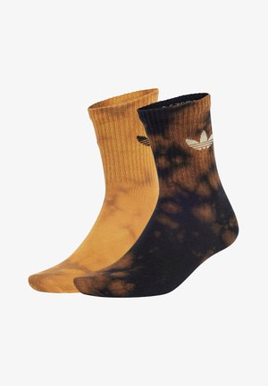 Calze di cotone in colori tie-dye a contrasto: una arancione con polsino a coste e una nera mescolata con arancione. Presentano accenti di logo bianchi.