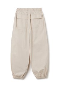 Beige, lichtgewicht stoffen broek met een elastische tailleband en taps toelopende boorden, voorzien van twee achterzakken met kleppen.