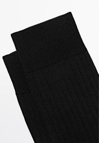 Calzini neri a coste con polsino e corpo strutturati, caratterizzati da un design senza cuciture e tessuto morbido, adatti per l'uso quotidiano.