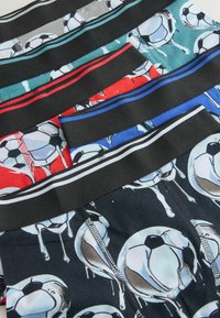 Ensemble de boxers pour garçons avec ceintures noires dotées de bandes colorées et imprimés de ballons de football dégoulinants sur des tissus de différentes couleurs.