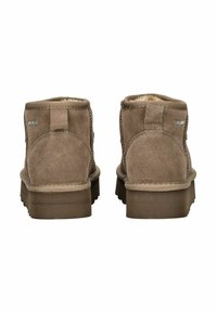 Botines de ante marrón con un interior suave, costuras reforzadas y una suela de goma texturizada. Cuenta con una lengüeta para facilitar su colocación.