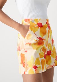 Shorts con motivo floreale in tonalità giallo, arancione e rosso, dotati di una vita strutturata e tasche laterali. Tessuto leggero in misto cotone.