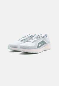 Zapatillas de running gris claro con parte superior de malla texturizada, acentos en blanco y suela rosa. Presentan cordones y una puntera reforzada para mayor durabilidad.