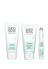 Three DADO SENS PURDERM products: a 100ml creamy cleanser, a 50ml normalizing cream, and a small roll-on anti-impurities treatment, all in white tubes with light green accents.