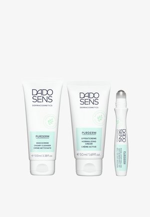 Drei DADO SENS PURDERM Produkte: ein 100 ml cremiger Reiniger, eine 50 ml normalisierende Creme und eine kleine Roll-on-Behandlung gegen Unreinheiten, alle in weißen Tuben mit hellgrünen Akzenten.