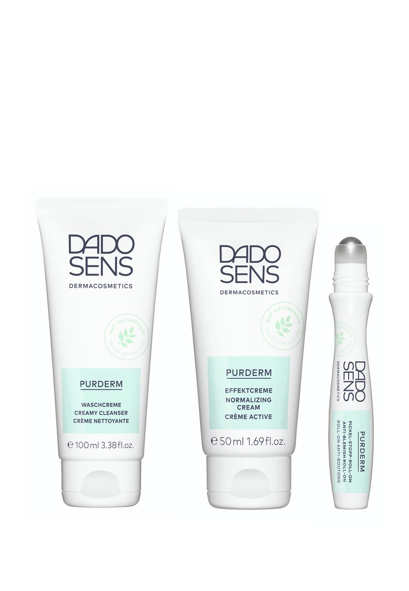 Three DADO SENS PURDERM products: a 100ml creamy cleanser, a 50ml normalizing cream, and a small roll-on anti-impurities treatment, all in white tubes with light green accents.