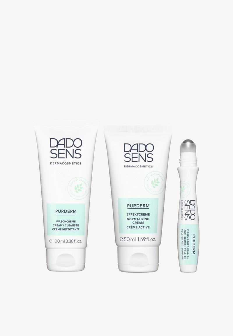 Three DADO SENS PURDERM products: a 100ml creamy cleanser, a 50ml normalizing cream, and a small roll-on anti-impurities treatment, all in white tubes with light green accents.