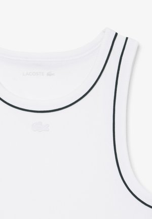 Witte mouwloze tanktop met zwarte bies langs de halslijn en armsgaten, met een klein reliëf Lacoste krokodillenlogo op de borst.
