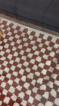 Texturerad matta med ett rutigt mönster i rött och vitt. Lugg är fluffig, med mjuka fibrer, och alternerande färgade rutor.