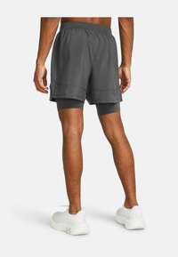 Gray athletic shorts with a built-in liner feature an elastic waistband and side mesh panels for breathability. White sneakers complement the look.