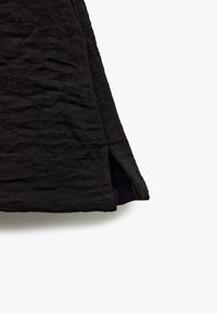Zwart textiel met een gewrongen uitstraling. Heeft een zijspleet aan de onderkant voor extra ontwerpelement.