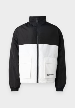 Color-blocked jacket with a black upper section and white lower section. Features a high collar, front zipper, and two front pockets.