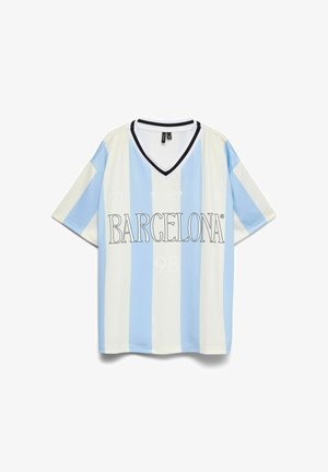 Kortærmet trøje i hvid med lyseblå lodrette striber. Har en sort V-halskrave og "BARCELONA" i fed skrift.