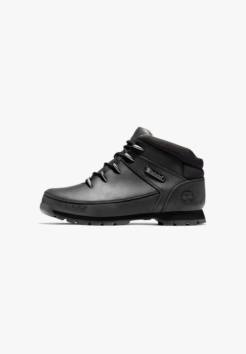 Botte de randonnée noire de hauteur moyenne avec col matelassé, œillets en métal, semelle robuste et logo Timberland sur le talon et le côté.